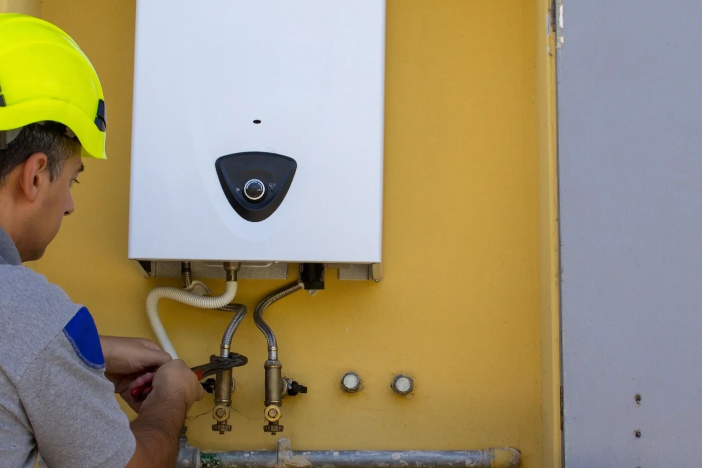 Installateur fixant une unité murale de climatisation dans un logement du 60